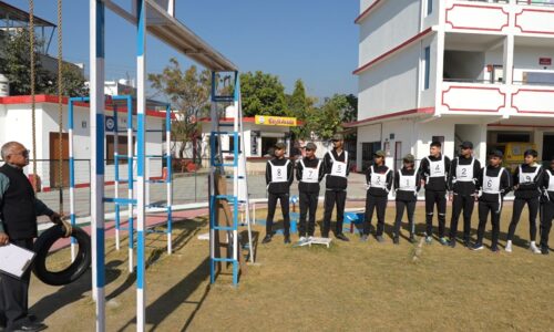 Outdoor setting with people in numbered sports attire standing in line and a man holding a tire.